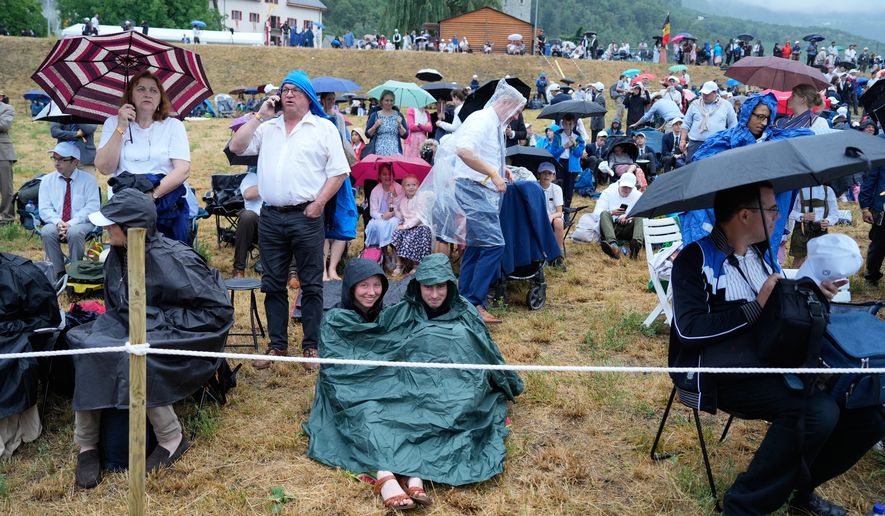 Faithful wait for the start of a consecration ceremony for four new bishops, outside a tent set up outside the Society of St. Pius X seminary, in Econe, Switzerland, Wednesday, July 1, 2026. (AP Photo/Baz Ratner)
