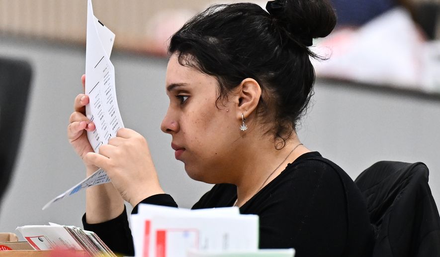 A worker inspects a ballot at the L.A. County Ballot Processing Center during the California primary election on Tuesday, June 2, 2026, in City of Industry, Calif. (AP Photo/William Liang)