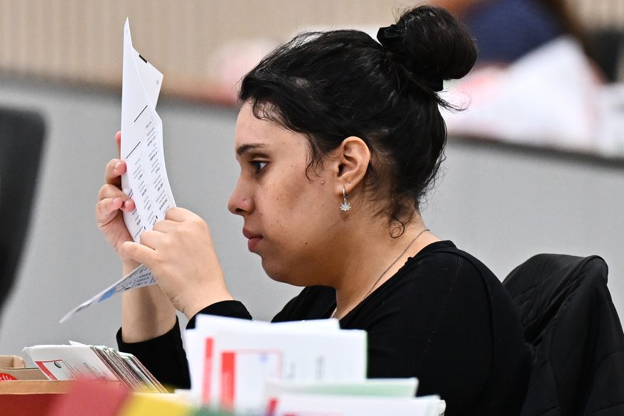 A worker inspects a ballot at the L.A. County Ballot Processing Center during the California primary election on Tuesday, June 2, 2026, in City of Industry, Calif. (AP Photo/William Liang)