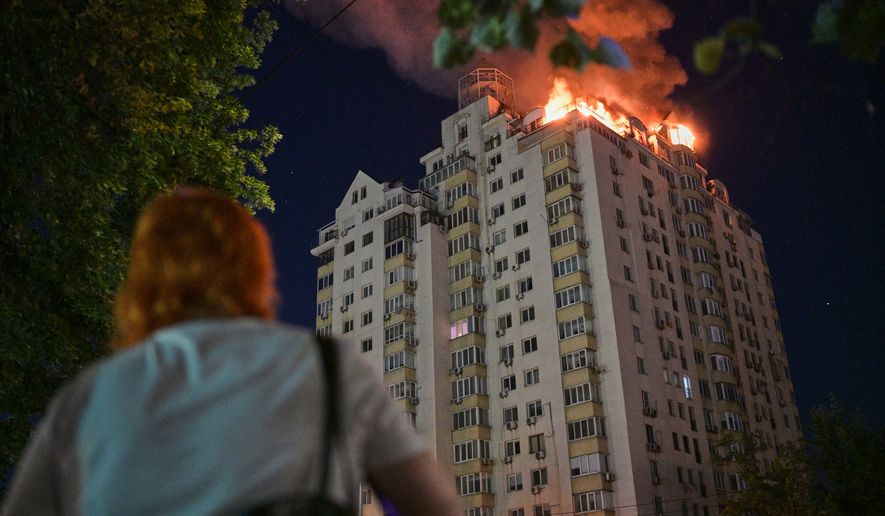A woman looks at an apartment building burning after a Russian missile attack in Kyiv, Ukraine, Thursday, July 2, 2026. (AP Photo/Danylo Antoniuk)