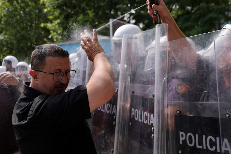 A riot police officer uses pepper spray against a protester during clashes at an anti-government rally in Tirana, Albania, Thursday, July 2, 2026. (AP Photo/Hameraldi Agolli)