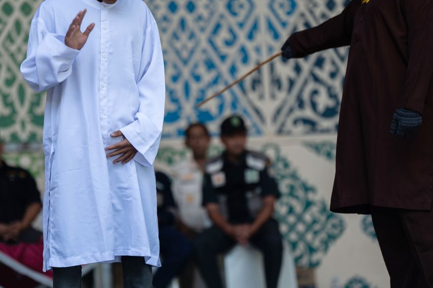 A man is publicly caned after he was convicted of violating Islamic law by kissing during a TikTok livestream, in Banda Aceh, Indonesia, Thursday, July 2, 2026. (AP Photo/Reza Saifullah)