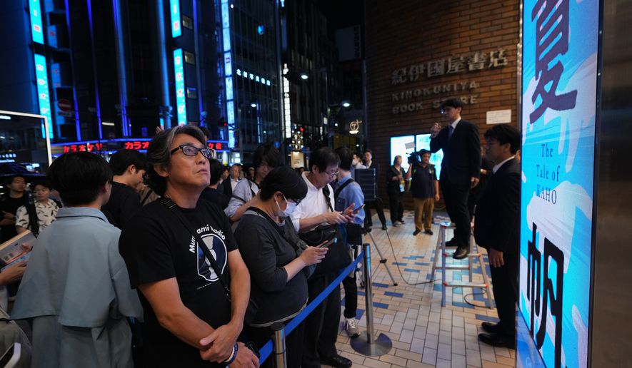 People attend a countdown event to receive copies they pre-purchased, of Haruki Murakami's new book, titled "The Tale of KAHO" after the clock strikes midnight, at a Kinokuniya bookstore in Tokyo on Thursday, July 2, 2026. (AP Photo/Hiro Komae)