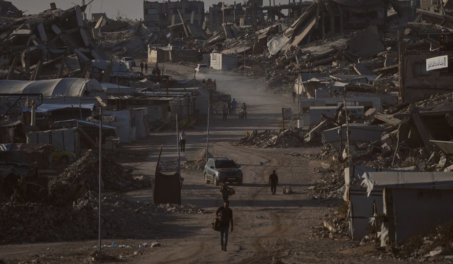 Palestinians walk along a road surrounded by buildings destroyed in Israeli military strikes during the Israel-Hamas war, in Jabaliya, Gaza Strip, Thursday, July 2, 2026. (AP Photo/Jehad Alshrafi)