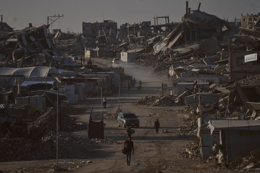 Palestinians walk along a road surrounded by buildings destroyed in Israeli military strikes during the Israel-Hamas war, in Jabaliya, Gaza Strip, Thursday, July 2, 2026. (AP Photo/Jehad Alshrafi)