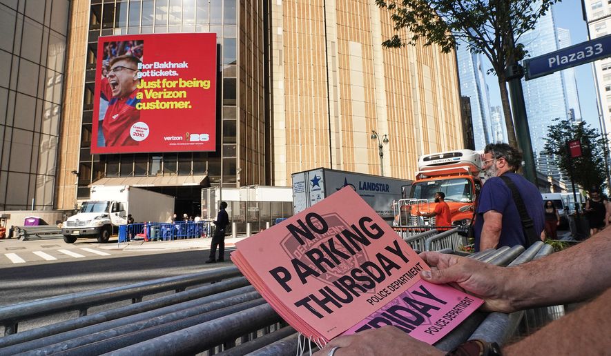 A worker holds "No Parking" signs prior to posting as trucks fill the loading dock outside New York's Madison Square Garden, Wednesday, July 1, 2026. (AP Photo/Richard Drew)