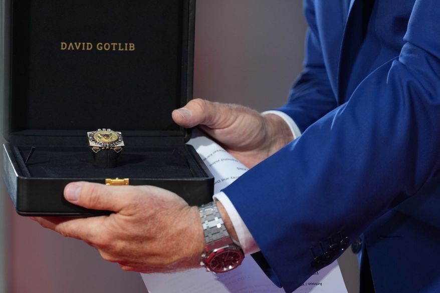 U.S. Ambassador to Belgium Bill White presents a ring designed for U.S. President Donald Trump and crafted by Antwerp diamond designer David Gotlib, during the America 250 event in Brussels, Sunday, June 28, 2026. (AP Photo/Virginia Mayo)