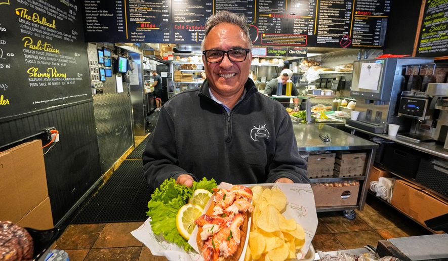Principal Paul Barker serves lobster rolls to World Cup tourists at Pauli's sandwich shop in the North End of Boston, Wednesday, June 24, 2026. (AP Photo/Martin Meissner)