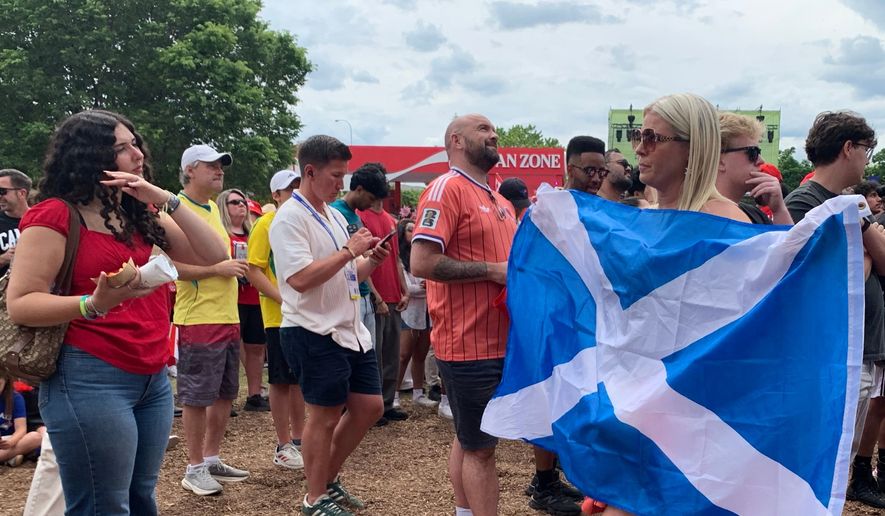 Gary Bishop of Glasgow, Scotland, center right, watches a screen showing the World Cup Group B soccer match between Switzerland and Canada during the FIFA Fan Festival on Wednesday, June 24, 2026, in Toronto. (AP Photo/Mike Householder)