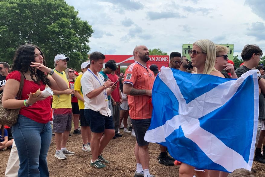 Gary Bishop of Glasgow, Scotland, center right, watches a screen showing the World Cup Group B soccer match between Switzerland and Canada during the FIFA Fan Festival on Wednesday, June 24, 2026, in Toronto. (AP Photo/Mike Householder)