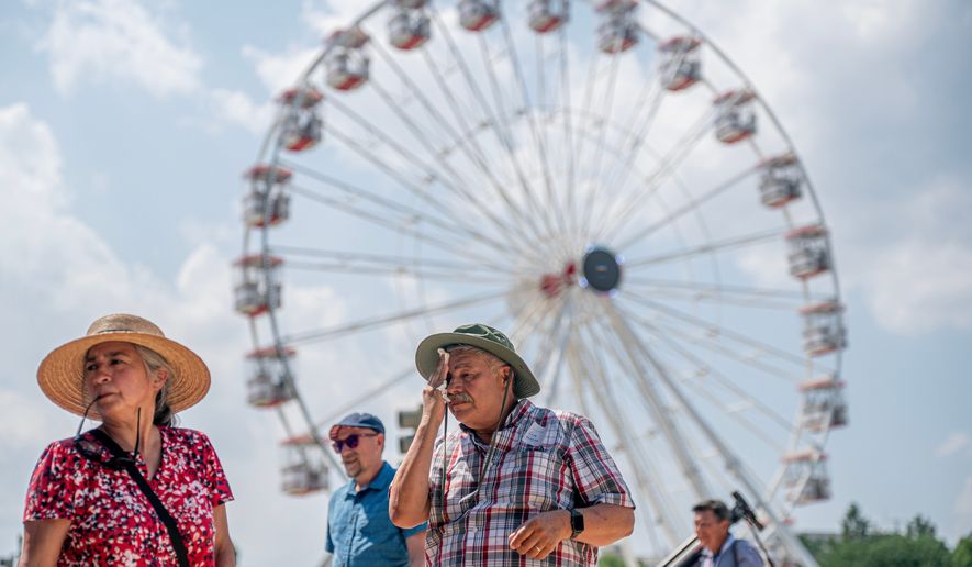 Visitors react to the heat while attending the Great American State Fair on the National Mall, Wednesday, July 1, 2026, in Washington. (AP Photo/Nathan Howard)