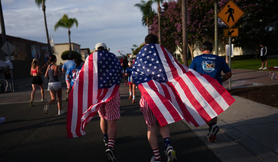 Runners draped in American flags participate in a run on Independence Day in Huntington Beach, Calif., Saturday, July 4, 2026. (AP Photo/Jae C. Hong)