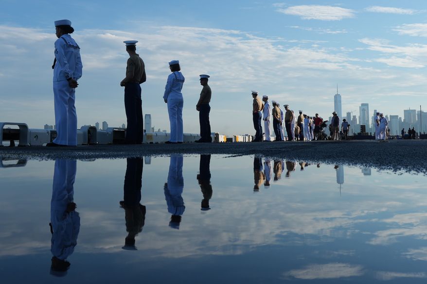 Military personnel stand on the wet flight deck of the USS Kearsarge (LHD-3) anchored in the New York harbor ahead of Sail250, a gathering of tall ships and military ships honoring America's 250th Anniversary, Saturday, July 4, 2026, in New York. (AP Photo/Frank Franklin II)