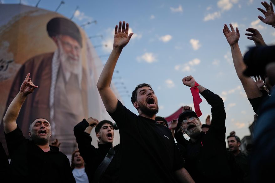 Mourners chant slogans while gathered in Islamic Revolution Square for the funeral procession of the slain Iranian Supreme Leader Ayatollah Ali Khamenei beneath a billboard depicting Khamenei in Tehran, Iran, Monday, July 6, 2026. (AP Photo/Altaf Qadri)