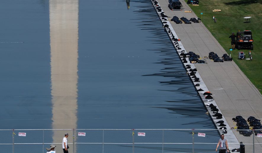 Workers install fireworks along the edge of the Lincoln Memorial Reflecting Pool ahead of the America 250 July 4th celebration on the National Mall, Thursday, July 2, 2026, in Washington. (AP Photo/Nathan Howard)