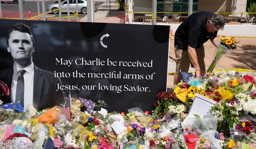 FILE - A well-wisher places flowers at a makeshift memorial set up for Charlie Kirk at Turning Point USA headquarters, Sept. 11, 2025, in Phoenix. (AP Photo/Ross D. Franklin, File)