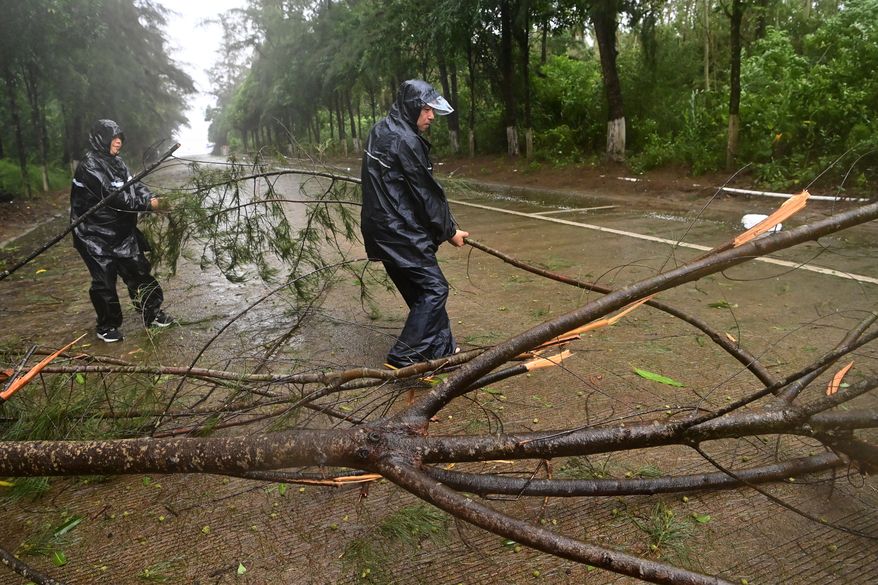 In this photo released by Xinhua News Agency, workers clear up a fallen tree along a road in Jiangping town, Dongxing of Fangchenggang, south China's Guangxi Zhuang Autonomous Region on Saturday, July 4, 2026, after a severe weather system was affecting the area. (Lu Boan/Xinhua via AP)