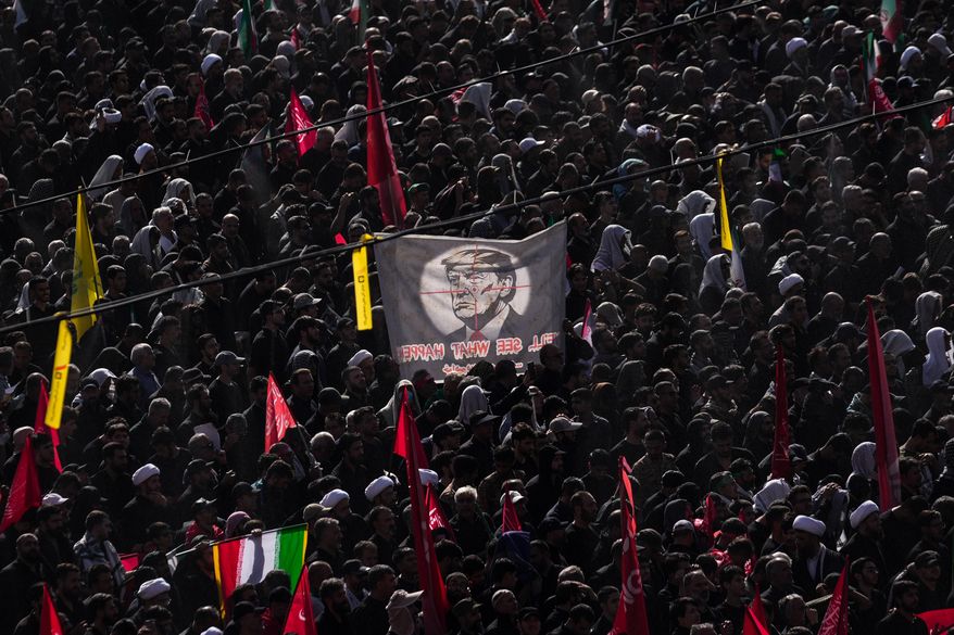 A banner depicting President Donald Trump is held aloft as mourners gather during funeral prayers held as part of the dayslong funeral ceremonies for the slain Iranian Supreme Leader Ayatollah Ali Khamenei and members of his family outside the Imam Khomeini Mosalla Grand Mosque in Tehran, Iran, Sunday, July 5, 2026. (AP Photo/Altaf Qadri)