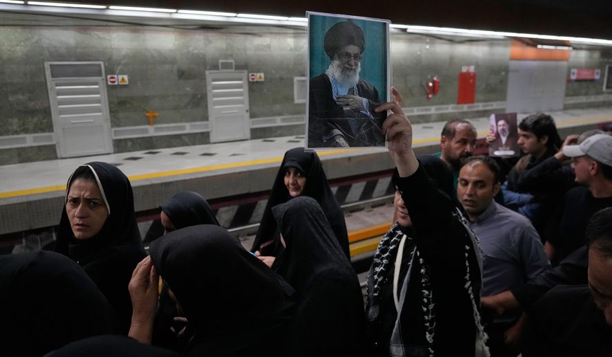 A woman holds a picture of the late Iranian Supreme Leader Ayatollah Ali Khamenei as she walks through a subway station with other mourners on their way to the funeral procession in Tehran, Iran, Monday, July 6, 2026. (AP Photo/Vahid Salemi)