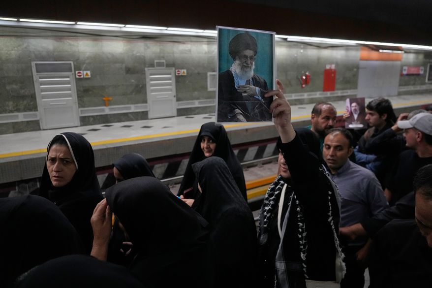 A woman holds a picture of the late Iranian Supreme Leader Ayatollah Ali Khamenei as she walks through a subway station with other mourners on their way to the funeral procession in Tehran, Iran, Monday, July 6, 2026. (AP Photo/Vahid Salemi)