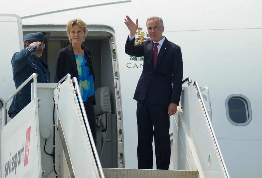 Canada Prime Minister Mark Carney waves as he and Diana Fox Carney board a government plane in Ottawa, Monday, July 6, 2026. (Adrian Wyld/The Canadian Press via AP)