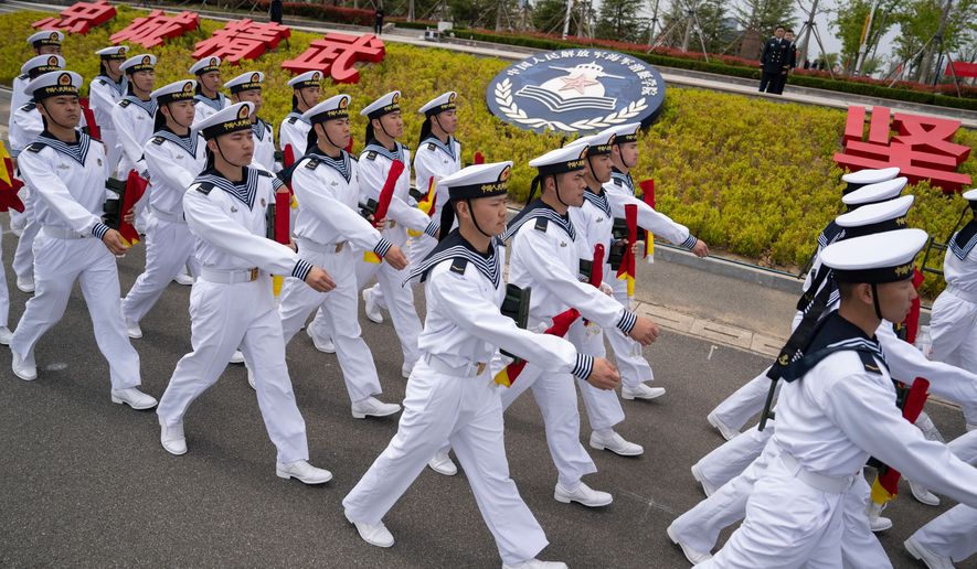 Sailors march past the insignia for the People's Liberation Army (PLA)'s naval submarine academy during a tour arranged for foreign journalists a day before the opening of the West Pacific Naval Symposium in Qingdao in eastern China's Shandong province, Sunday, April 21, 2024. (AP Photo/Ng Han Guan, File)