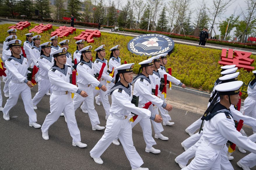 Sailors march past the insignia for the People's Liberation Army (PLA)'s naval submarine academy during a tour arranged for foreign journalists a day before the opening of the West Pacific Naval Symposium in Qingdao in eastern China's Shandong province, Sunday, April 21, 2024. (AP Photo/Ng Han Guan, File)