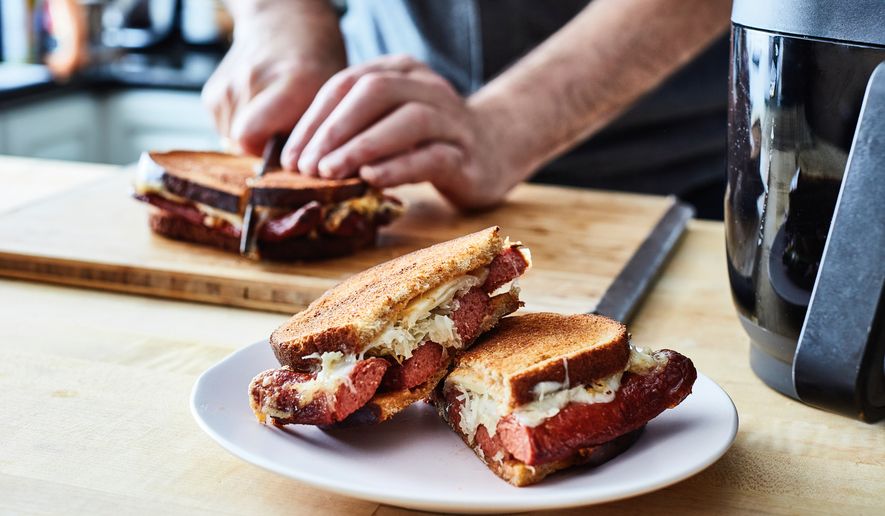 This image released by Voracious shows a recipe for Reuben hot dogs from “The Instant Air Fryer Bible" by Bruce Weinstein and Mark Scarbrough. (Eric Medsker/Voracious via AP)