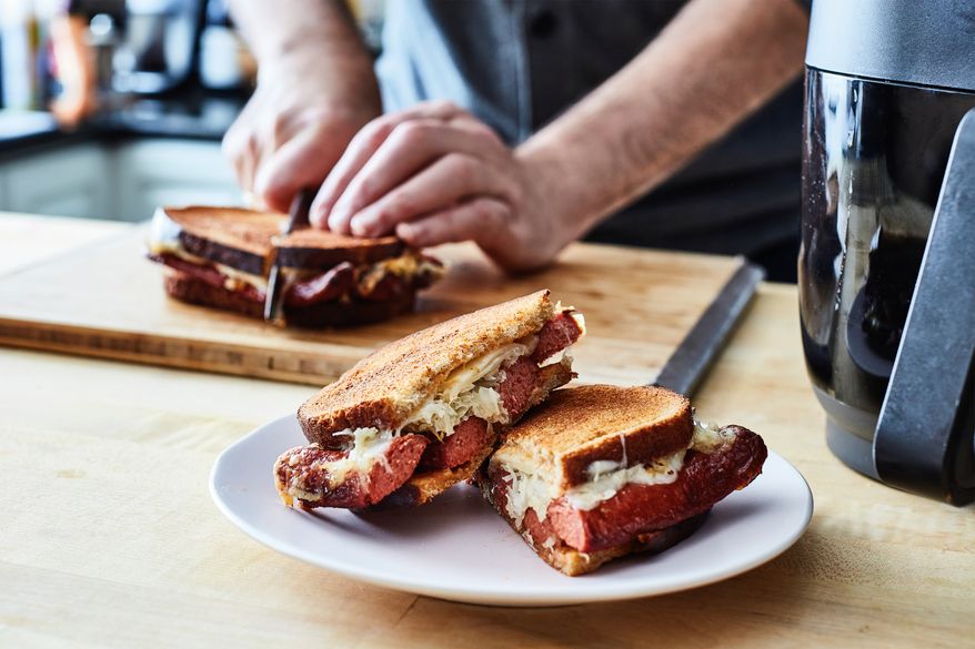 This image released by Voracious shows a recipe for Reuben hot dogs from “The Instant Air Fryer Bible" by Bruce Weinstein and Mark Scarbrough. (Eric Medsker/Voracious via AP)