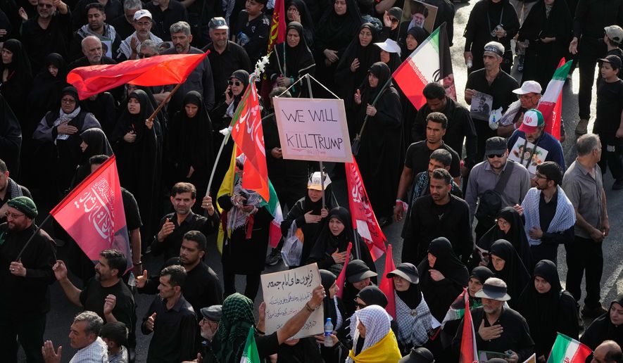 A mourner carries a sign reading "We Will Kill Trump" as people make their way to the funeral procession of the slain Iranian Supreme Leader Ayatollah Ali Khamenei in Tehran, Iran, Monday, July 6, 2026. (AP Photo/Vahid Salemi)