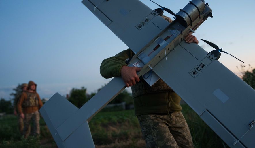 A Ukrainian serviceman of K-2 brigade of the Unmanned Systems Forces carries a midrange drone on takeoff position before flying towards Russian positions at the frontline in Donetsk region, Ukraine, Monday, June 22, 2026. (AP Photo/Evgeniy Maloletka)
