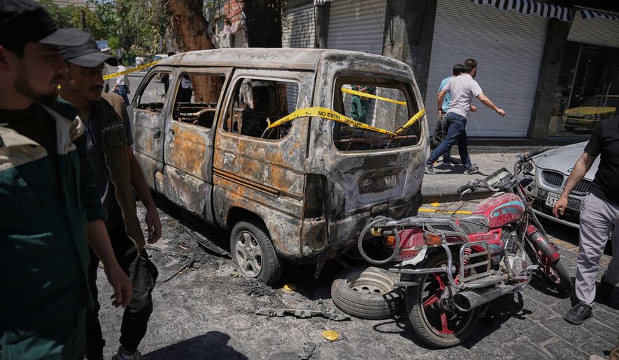 Syrian security personnel inspect a burned vehicles near the Four Seasons Hotel after two explosions rocked the area earlier while Syrian President Ahmad al-Sharaa was meeting French President Emmanuel Macron at the presidential palace, in Damascus, Syria, Tuesday, July 7, 2026. (AP Photo/Omar Albam)