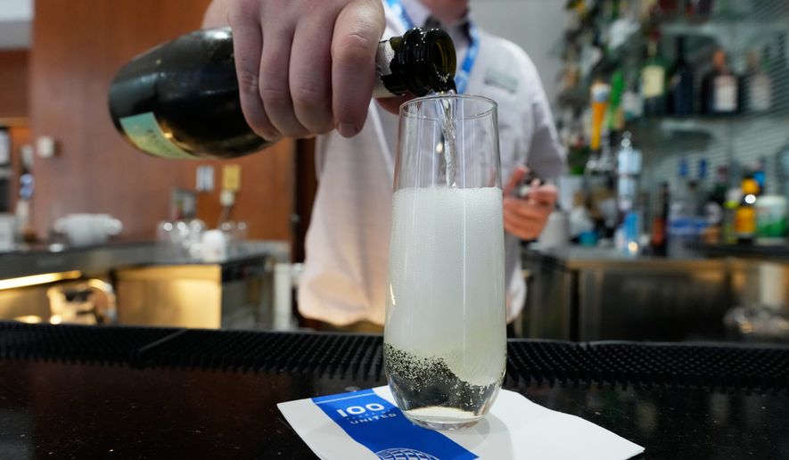 A bartender pours a glass of sparkling wine at the United Club lounge, Monday, June 29, 2026, in Minneapolis, Minn. (AP Photo/Chris Carlson)