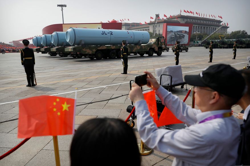 Spectators wave Chinese flags as military vehicles carrying JL-2 submarine-launched missiles roll during a parade to commemorate the 70th anniversary of the founding of Communist China in Beijing, Oct. 1, 2019. (AP Photo/Mark Schiefelbein, File)