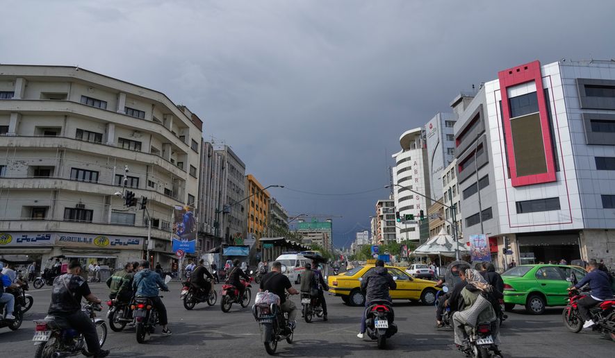 FILE - Motorbikes and cars pass through an intersection in downtown Tehran, Iran, May 17, 2026. (AP Photo/Vahid Salemi, File)