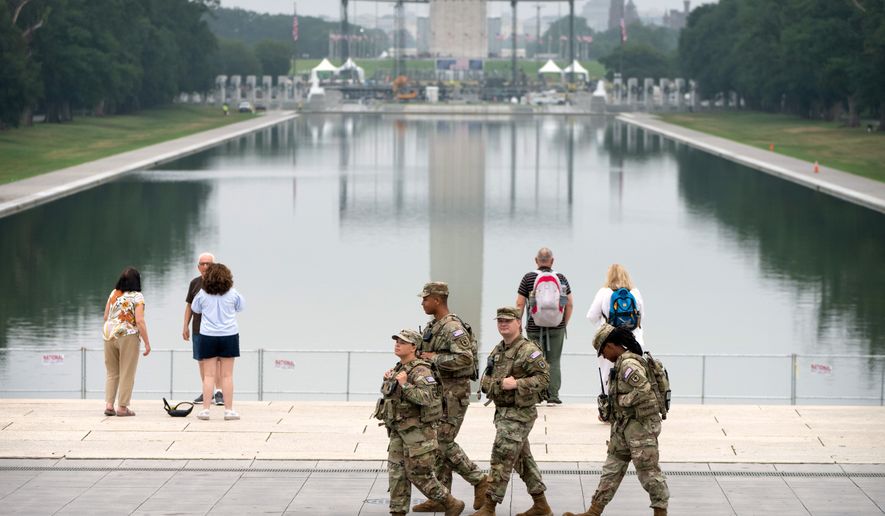 National Guard members walk past the Lincoln Memorial Reflecting Pool, Tuesday, July 7, 2026, in Washington. (AP Photo/Mark Schiefelbein)