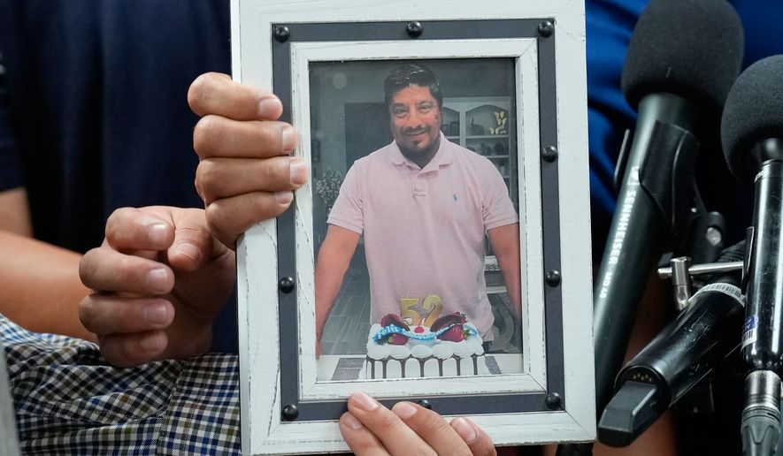 Ronaldo Salgado and Lorenzo Jr., sons of Lorenzo Salgado Araujo, hold a photograph of their father during a news conference Wednesday, July 8, 2026, in Houston. (AP Photo/David J. Phillip)