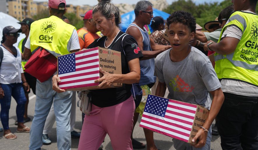 People affected by the earthquakes carry U.S. humanitarian aid after receiving it in La Guaira, Venezuela, Wednesday, July 8, 2026. (AP Photo/Ariana Cubillos)