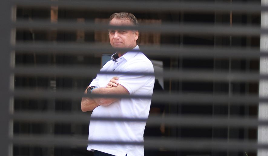 Brazil's former President Jair Bolsonaro stands at the entrance of his home while he is under house arrest in Brasilia, Brazil, Sept. 2, 2025. (AP Photo/Luis Nova, File)