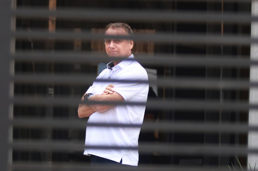 Brazil's former President Jair Bolsonaro stands at the entrance of his home while he is under house arrest in Brasilia, Brazil, Sept. 2, 2025. (AP Photo/Luis Nova, File)
