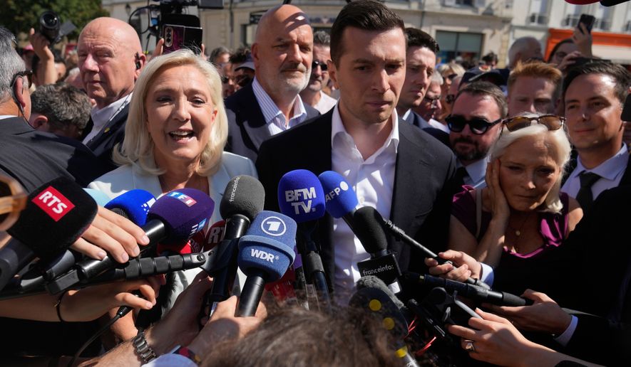 Far-right leader Marine Le Pen and Far-right party National Rally president Jordan Bardella answer journalists as they arrive to visit a market in La Fleche, western France Wednesday, July. 8, 2026. (AP Photo/Michel Euler)