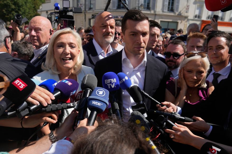 Far-right leader Marine Le Pen and Far-right party National Rally president Jordan Bardella answer journalists as they arrive to visit a market in La Fleche, western France Wednesday, July. 8, 2026. (AP Photo/Michel Euler)