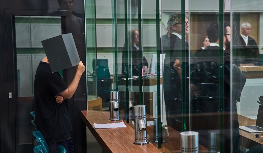 The defendant covering his face in the court during a trial against an online predator network of men accused of using chat groups to share tips on how to drug and rape women, in Berlin, Germany, Wednesday, July 8, 2026. (AP Photo/Ebrahim Noroozi)