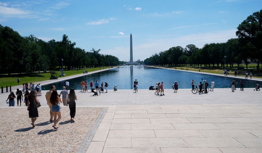 Visitors on the National Mall walk around the Reflecting Pool, between the Lincoln Memorial and the Washington Monument, Thursday, June 25, 2026, in Washington. (AP Photo/Manuel Balce Ceneta)