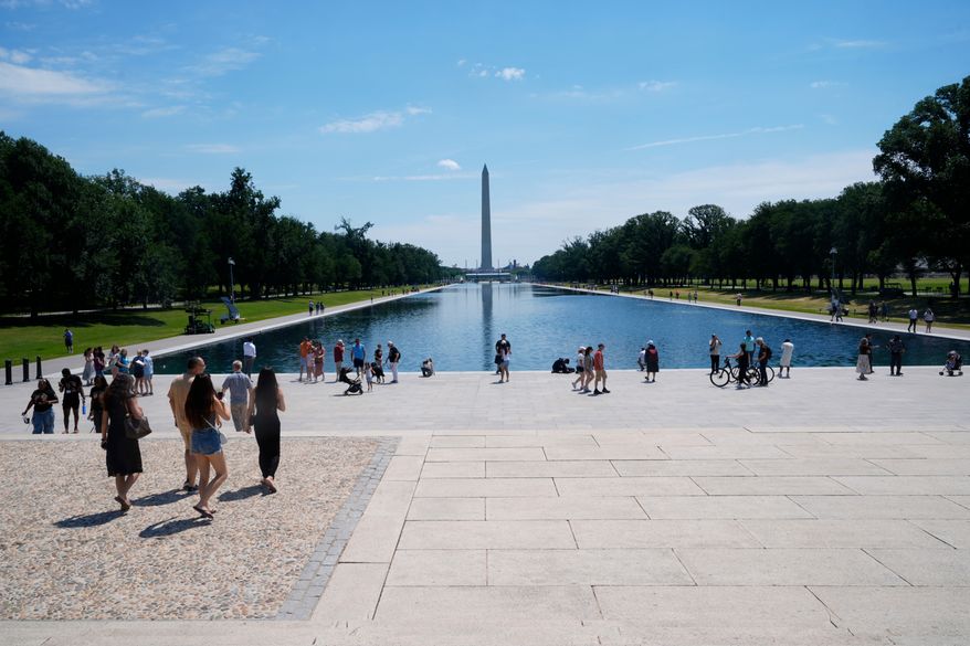 Visitors on the National Mall walk around the Reflecting Pool, between the Lincoln Memorial and the Washington Monument, Thursday, June 25, 2026, in Washington. (AP Photo/Manuel Balce Ceneta)