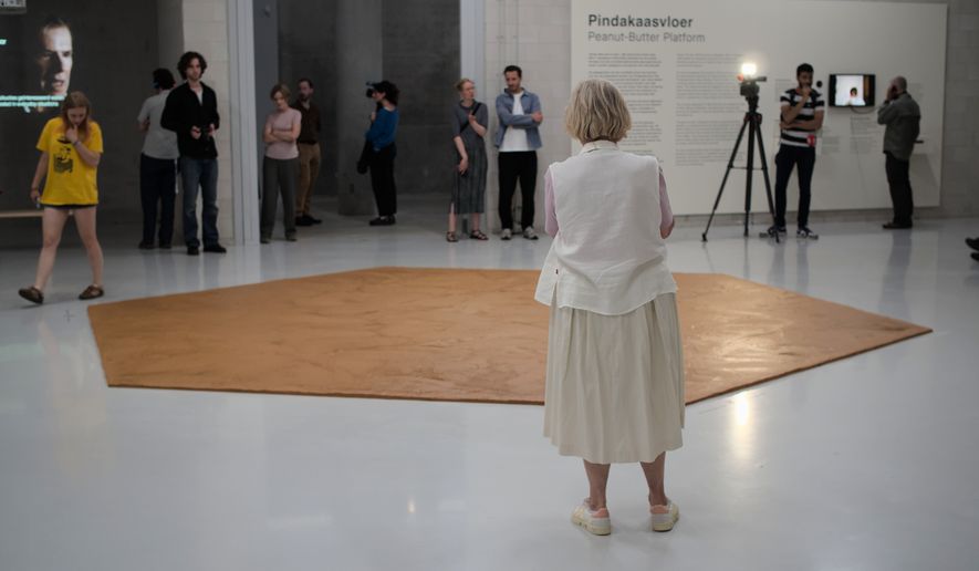 In this photo provided by Niels van der Pas, people look at the peanut butter floor spread across a museum floor in tribute to Dutch artist Wim T. Schippers, who died last month, in Rotterdam, the Netherlands, Thursday, July 9, 2026.(Niels van der Pas/via AP)