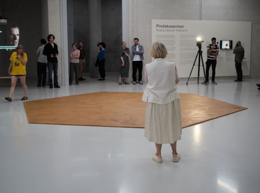 In this photo provided by Niels van der Pas, people look at the peanut butter floor spread across a museum floor in tribute to Dutch artist Wim T. Schippers, who died last month, in Rotterdam, the Netherlands, Thursday, July 9, 2026.(Niels van der Pas/via AP)