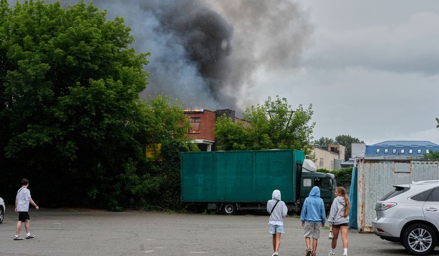 People look at a burning private enterprise following Russian drone attack in Kyiv, Ukraine, Wednesday, July 8, 2026. (AP Photo/Efrem Lukatsky)