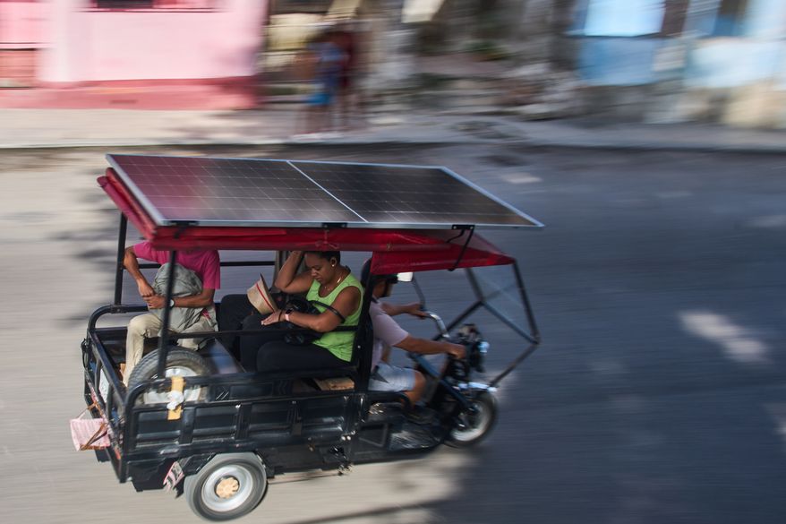 People ride in an electric tricycle equipped with a solar panel in Havana, Cuba, Friday, July 10, 2026. (AP Photo/Ramon Espinosa)