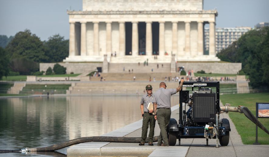 National Park Service workers stand near a pump placed next to the Lincoln Memorial Reflecting Pool, Friday, July 10, 2026, in Washington. (AP Photo/Mark Schiefelbein)